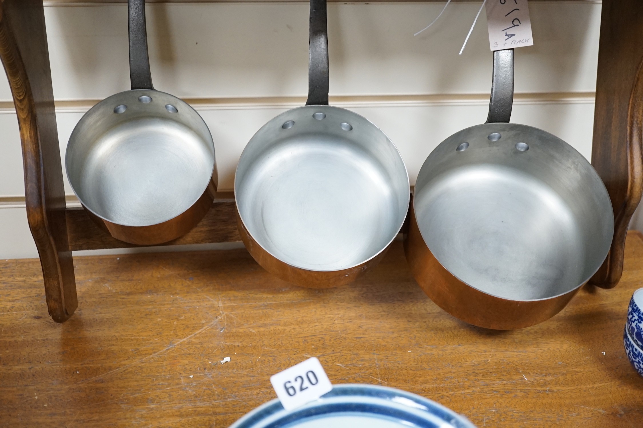 A set of three French copper saucepans, pendant from rack, 57cm wide